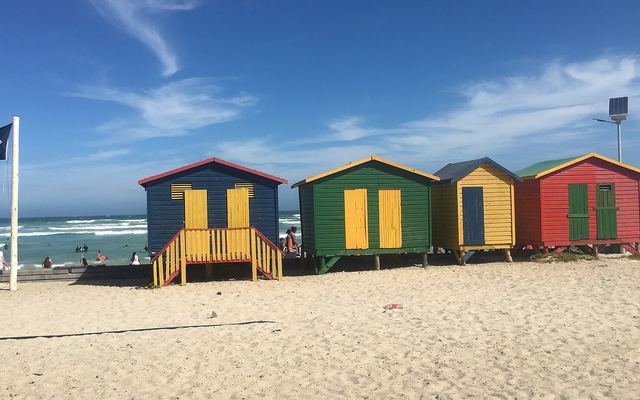 De rij felgekleurde strandhuisjes op het strand van Muizenberg