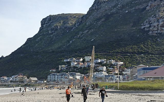 Surfers in het water bij Muizenberg met de kleurrijke strandhuisjes op de voorgrond
