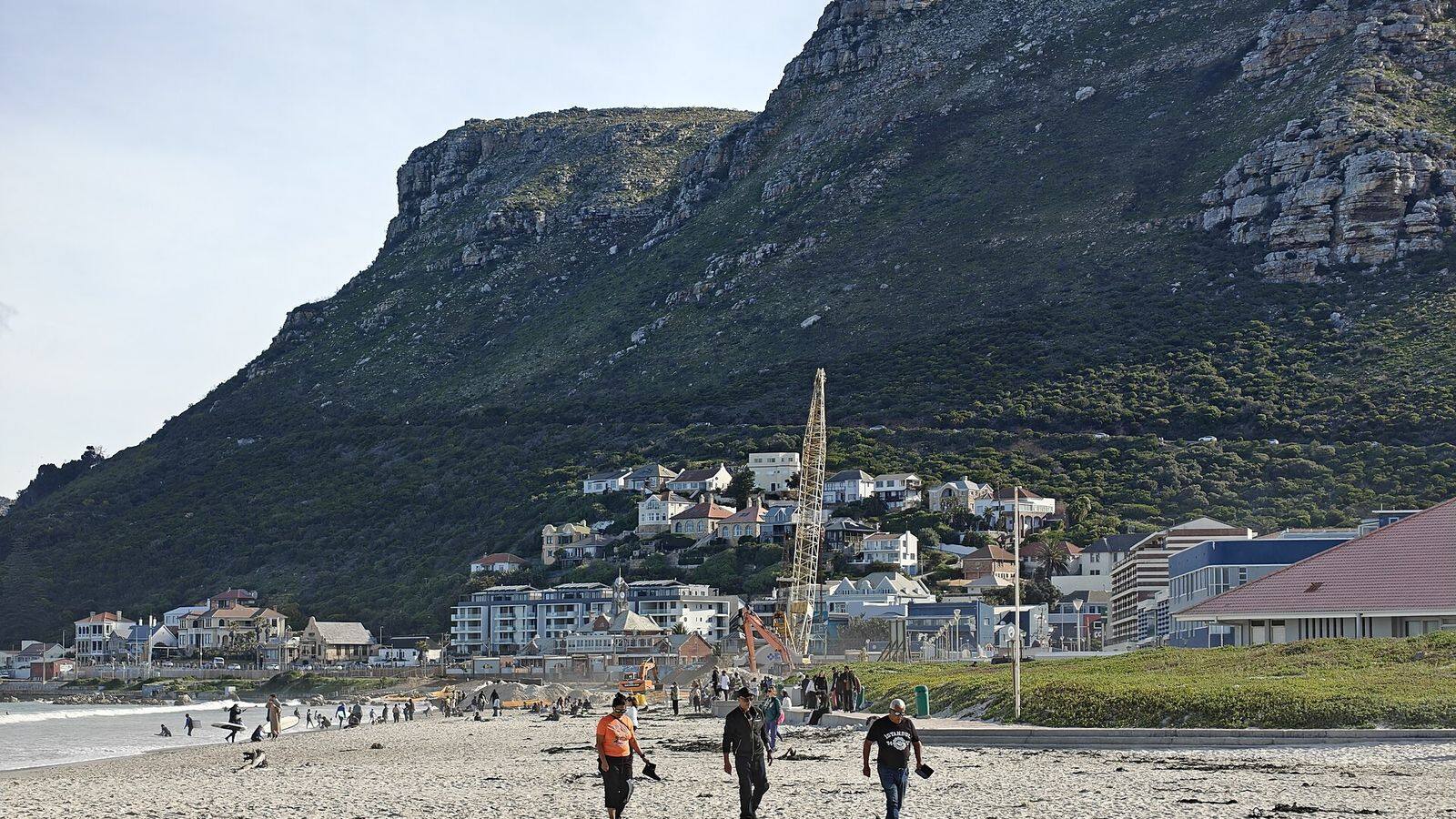 Surfers in het water bij Muizenberg met de kleurrijke strandhuisjes op de voorgrond