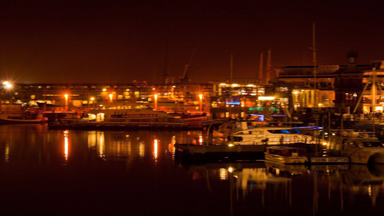 De V&A Waterfront in Kaapstad bij avond met verlichte restaurants aan het water