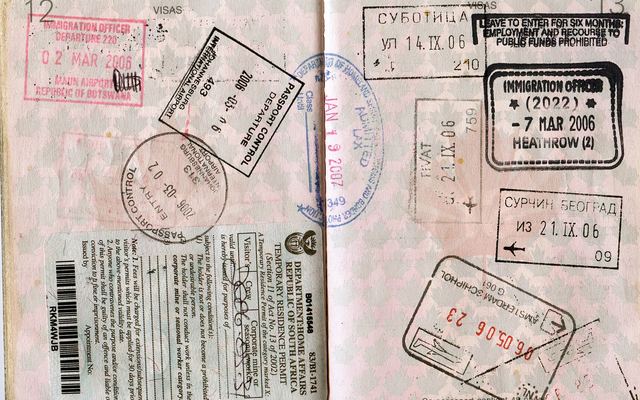 Paspoort met inreisstempels op een tafel naast een vliegticket